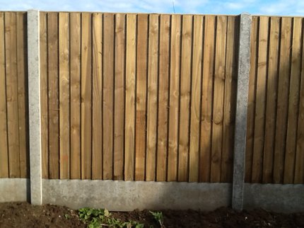Closeboard garden fence installation with concrete kickboards and posts